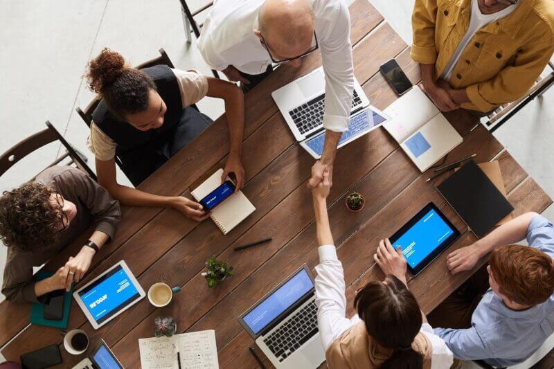 Overhead view of people sitting at a table with laptops and tablets