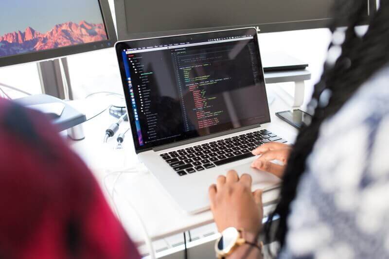 People sitting in front of a laptop looking at computer code